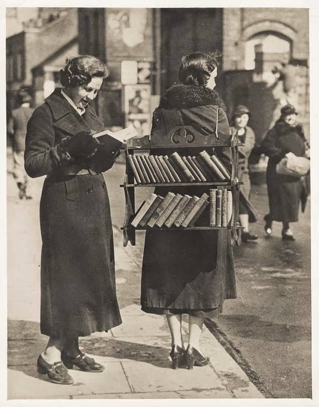 1930 年代倫敦街頭的行動圖書館，一位女子背著書架